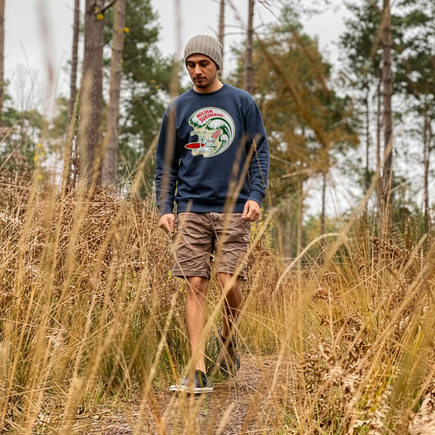 Man walking through a forest wearing a French navy Holden Surfboards sweatshirt.