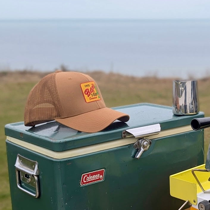 Caramel 1973 Baja 1000 cap on a Vintage green Coleman cooler outdoors