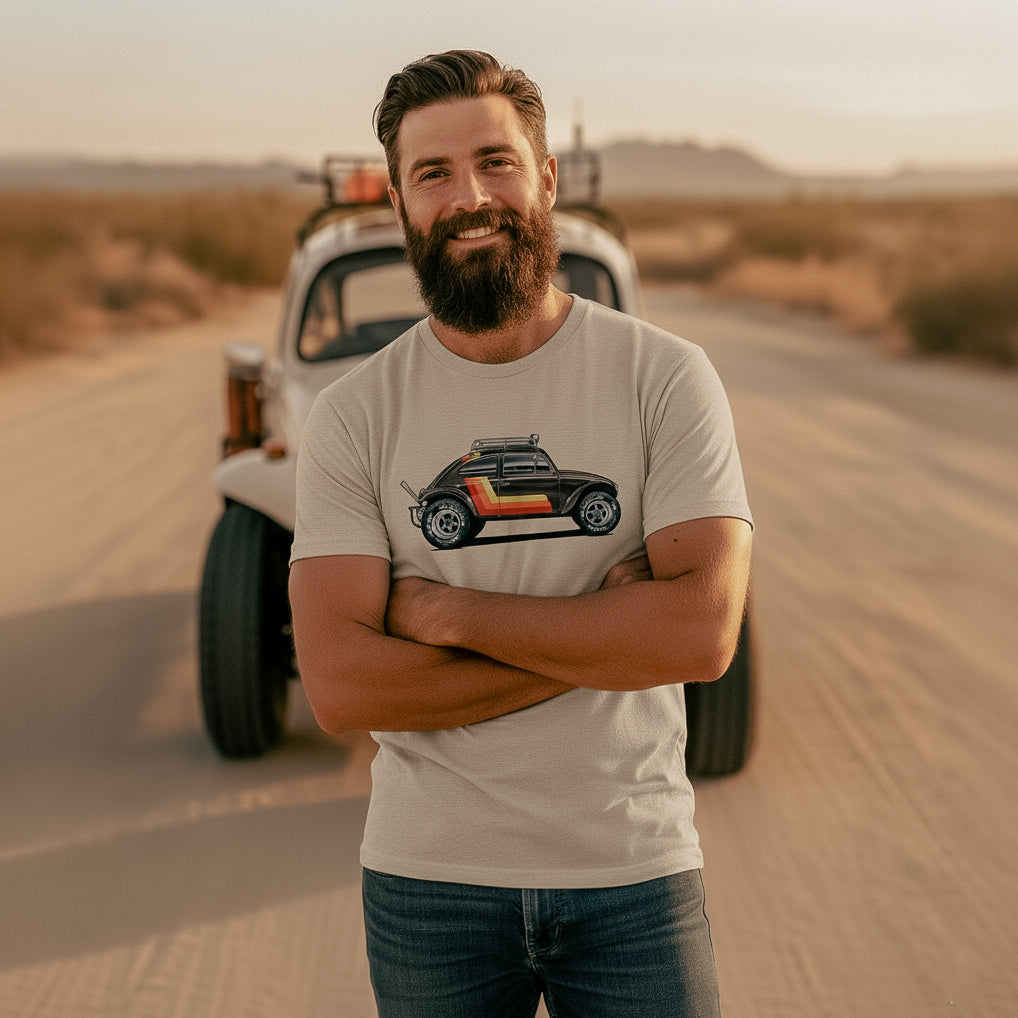 Man standing in a desert with a vintage Baja bug in the background, wearing a 'Stripes' Baja Bug T-shirt.