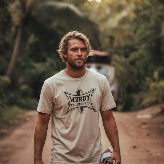 Man stands in front of a VW Bug with surfboards on the roof, wearing a Vintage style Wardy Surfboards T-shirt.