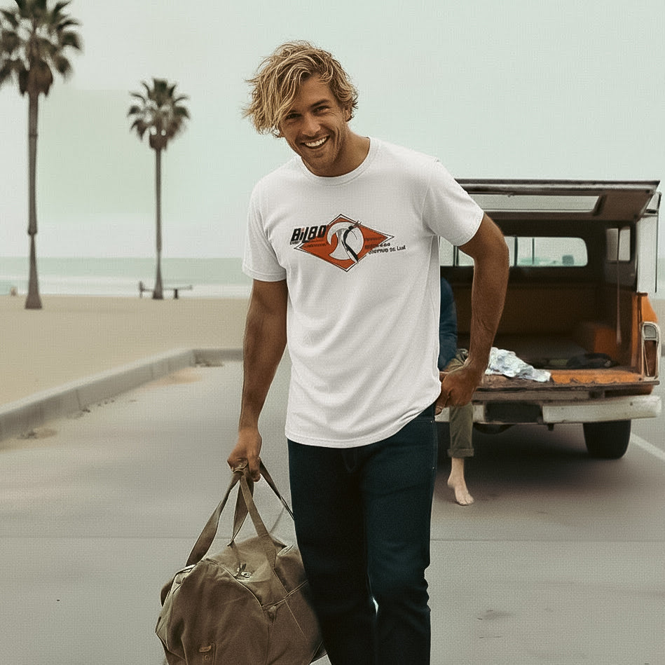 Man stands in front of a Chevy Camper Special Truck wearing a Vintage 1965-style Bilbo Surfboards T-shirt.