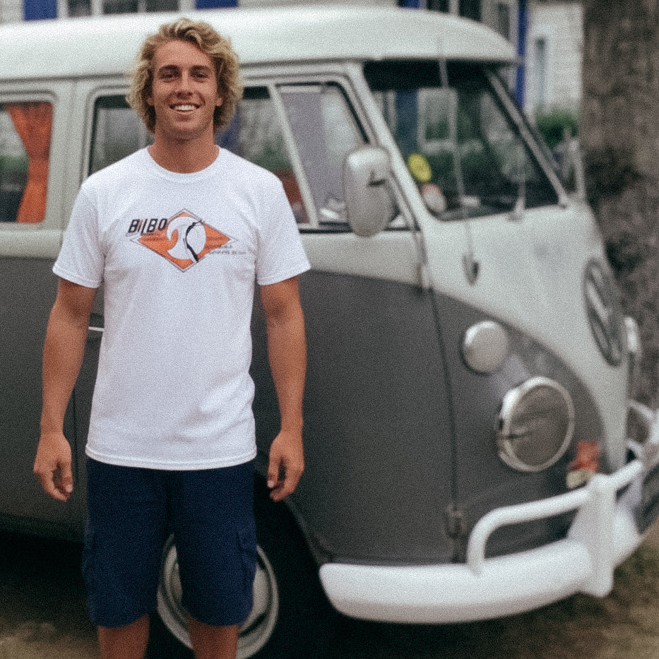 Man stands in front of a VW Split Screen Bus wearing a Vintage 1965-style Bilbo Surfboards T-shirt.