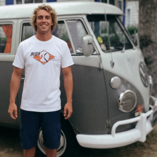 Man stands in front of a VW Split Screen Bus wearing a Vintage 1965-style Bilbo Surfboards T-shirt.
