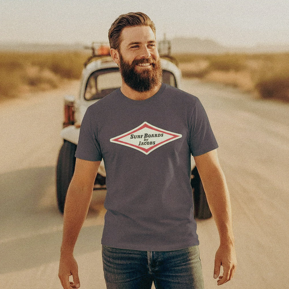 Man stands in front of a VW Baja Bug wearing a Vintage style Surfboards by Jacobs dark grey T-shirt.