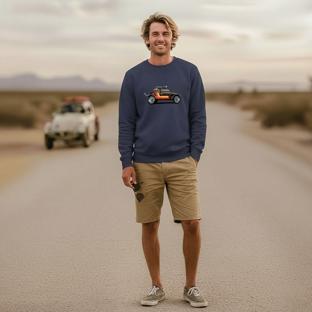 Man standing on a desert road wearing a navy 'Stripes' Baja Bug sweatshirt, with a vintage Baja Bug in the background.