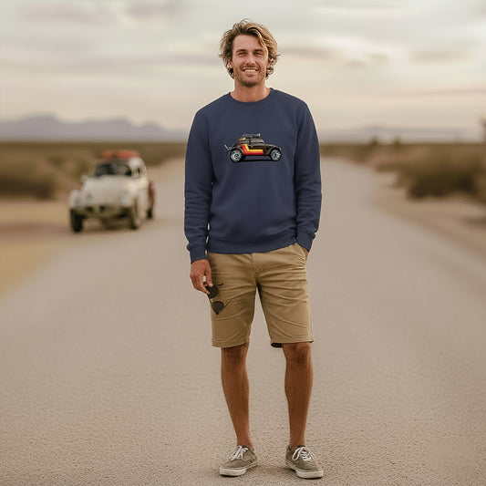 Man standing on a desert road wearing a navy 'Stripes' Baja Bug sweatshirt, with a vintage Baja Bug in the background.